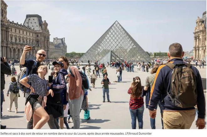 在卢浮宫金字塔前拍照留念的游客
