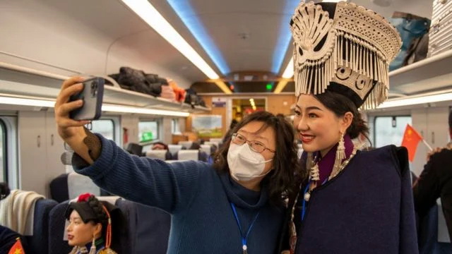 连接成都和昆明的新成昆铁路开通，带着口罩的乘客与穿着彝族传统服饰的女性自拍合照 ...