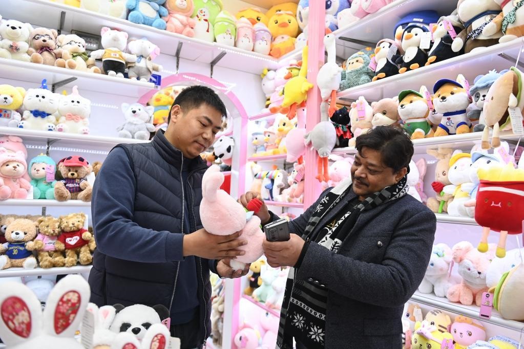 来自印度的客商拉贾(右)在义乌国际商贸城的一家玩具店铺内选购