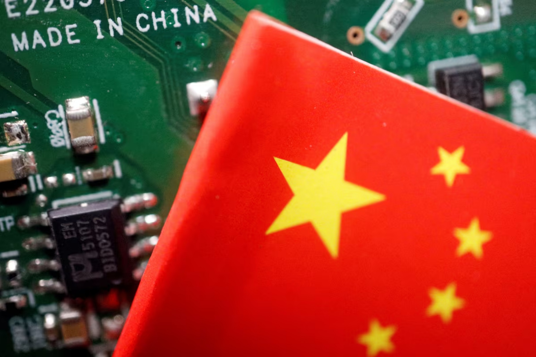 一块印刷电路板上印有“中国制造”字样，旁边悬挂着一面中国国旗